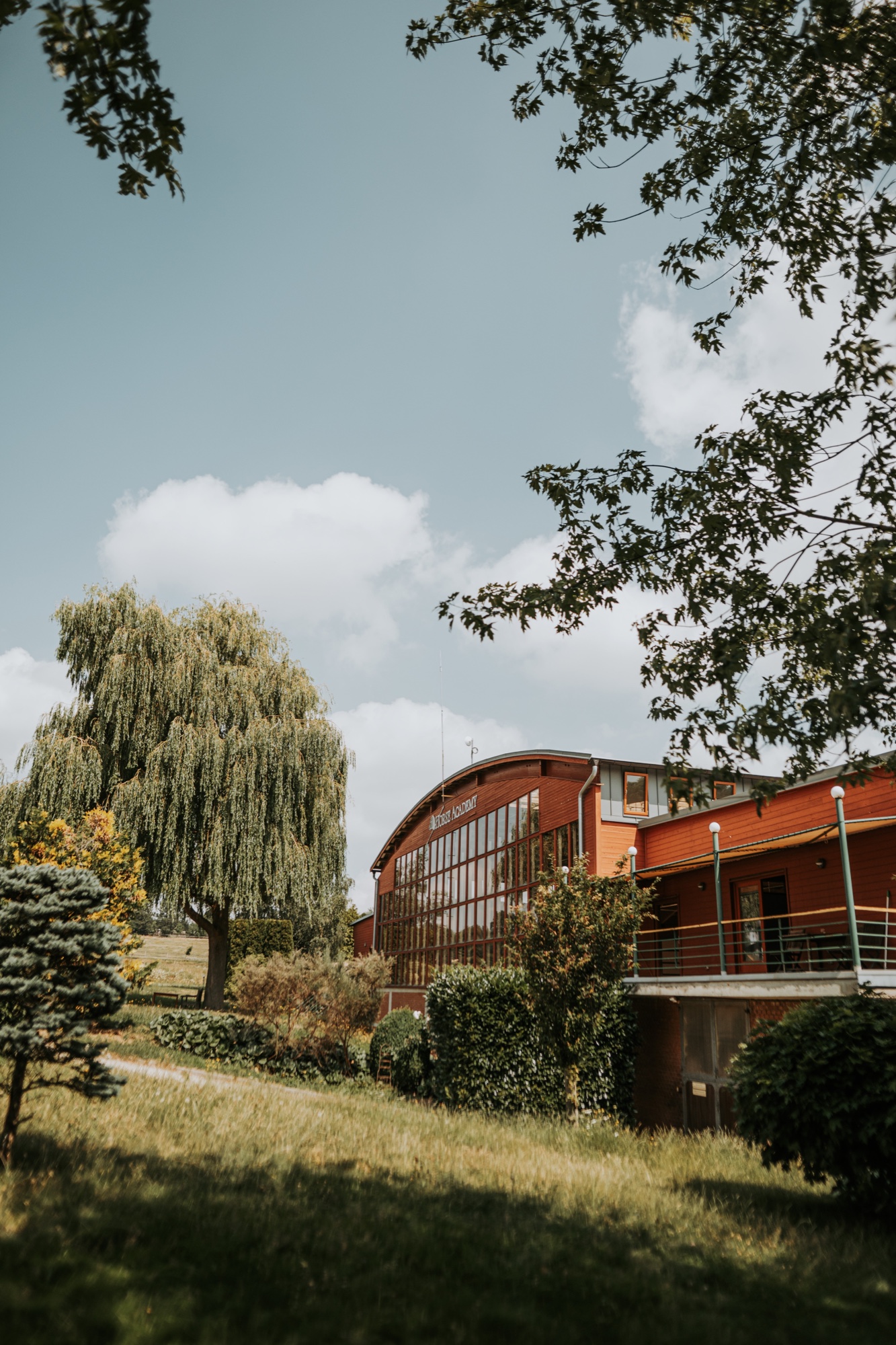 Budova jízdárny Horse Academy obklopená zelení